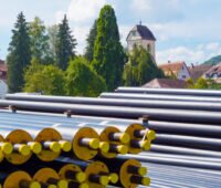 Fernwärmerohre vor Dorfkulisse in Breitenholz - Symbolbild für Infrastrukturinvestitionen von Kommunen nach dem LuKIFG