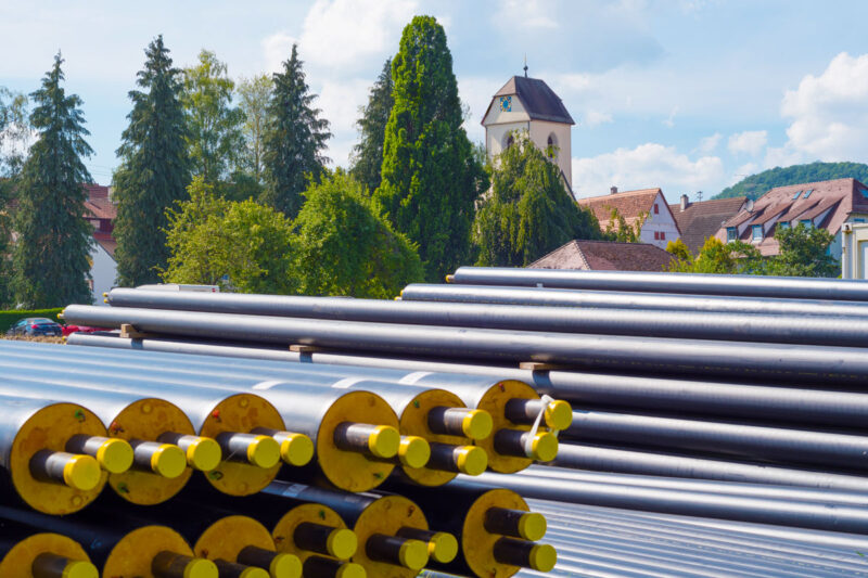 Fernwärmerohre vor Dorfkulisse in Breitenholz - Symbolbild für Infrastrukturinvestitionen von Kommunen nach dem LuKIFG