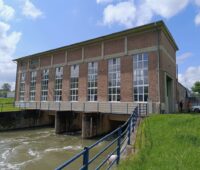 Foto zeigt Backstein-Gebäude, das über einem Fließgewässer errichtet ist - ein Wasserkraftwerk.