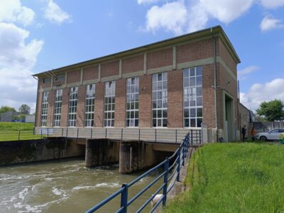 Foto zeigt Backstein-Gebäude, das über einem Fließgewässer errichtet ist - ein Wasserkraftwerk.
