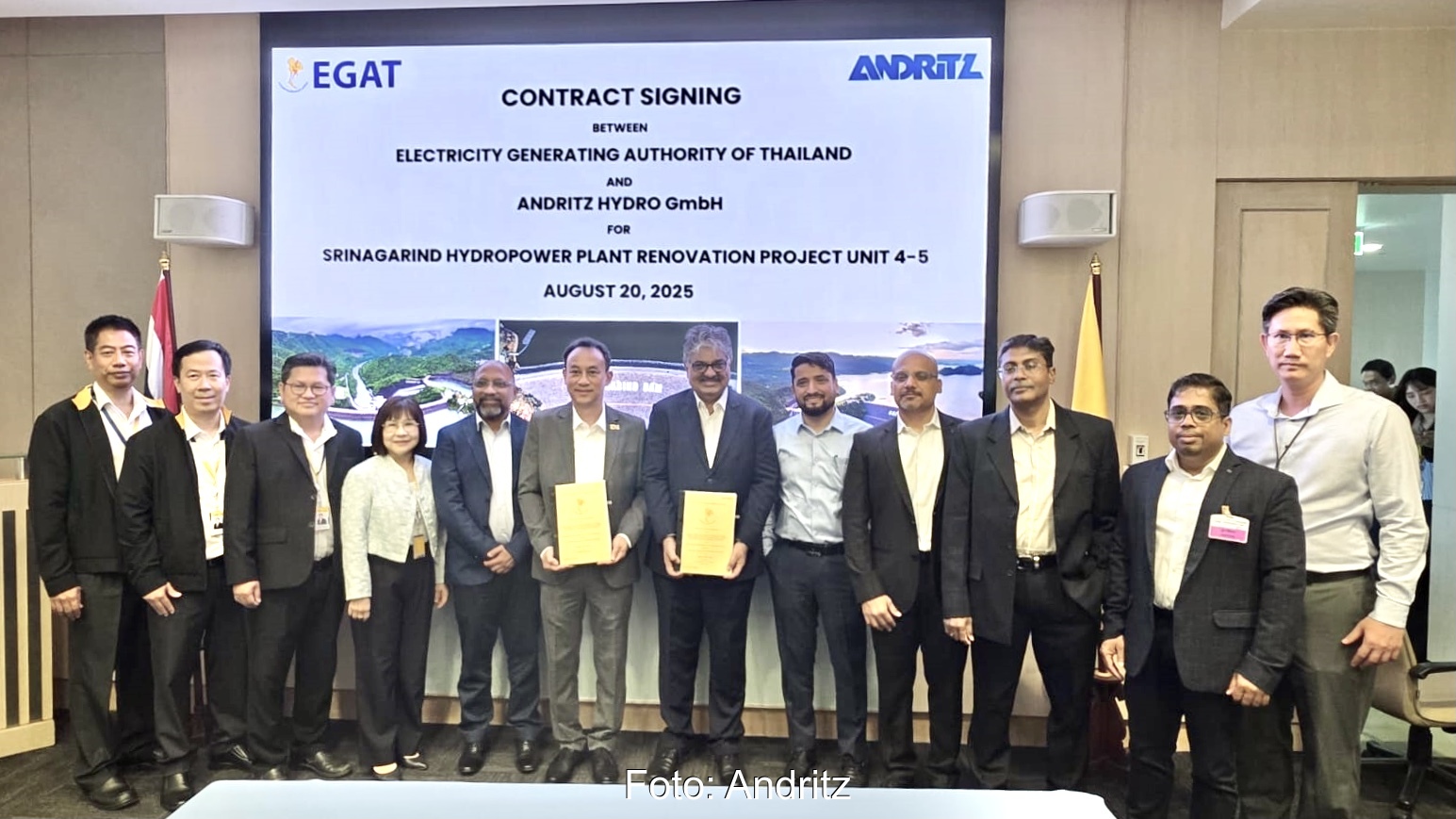 Verantwortliche von EGAT und Andritz Hydropower bei der Vertragsunterzeichnung "Modernisierung des Wasserkraftwerks Srinagarind" in Reihe aufgestellt vor einem Digital-Board an der Wand dahinter.