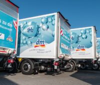 Die Hecks von vier Lkw mit blauem H2-Aufdruck und dm-Logo