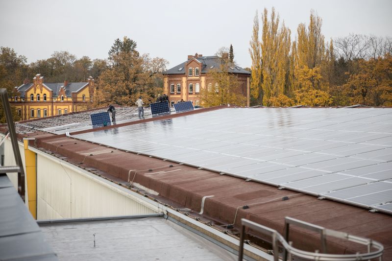 Montage von Solarmodulen auf einem hitorischen Wasserwerk im Herbstlaub.