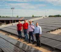 4 Personen inmitten einer gewerblichen PV-Großanlage.