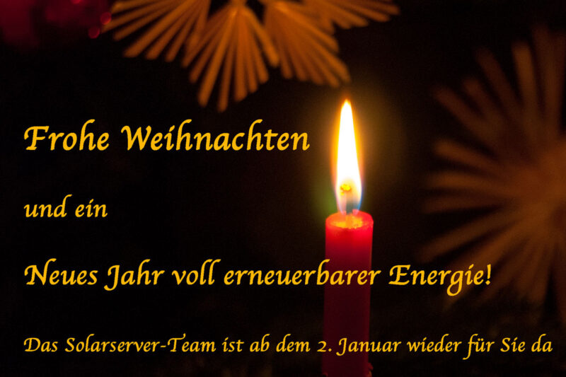 Brennende Kerze vor Weihnachtssternen. Schrift mit Weihnachts- und Neujahrsgrüßen.