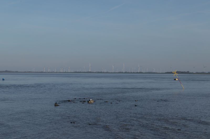 Im Vordergrund im Eidersperrwerk an der Nordsee. Im Hintergrund schememhaft Windkraftanlagen