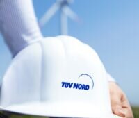 Zu sehen ist ein Schutzhelm mit TÜV Nord Logo als Symbol für den komplexen Bau von Windenergie-Anlagen in Störfallbetrieben.