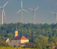 Windpark in Bayern, Zöschingen, drei Windenergie-Anlagen hinter einer Kirche