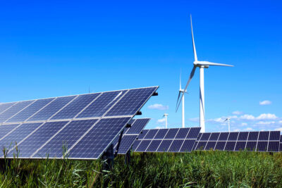 Freiflächen-Photovoltaikanlage vor Windenergieanlagen - Symbolbild für Beschleunigungsgebiete für beide Technologien