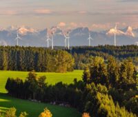 Windenergie-Anlagen in Bayern vor Alpen-Kulisse im Sonnenuntergang