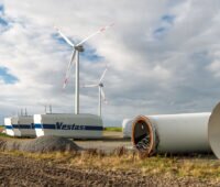 Repowering einer Windenergieanlage. Im Vordergrund Teile einer abgebauten Anlage. In Hintergrund steht bereits eine neue Windturbine.