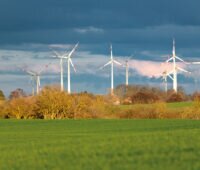 Windpark in Mecklenburg-Vorpommern bei Aprilwetter. Vordergrund: Grünes Getreidefeld, Himmel Dunkle Wolken.