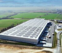 Luftbild eines Logistikzentrums mit PV-Modulen gedeckt.