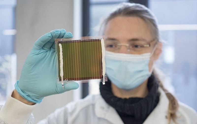 Zu sehen ist eine Forscherin, die eine Solarzelle mit Tandem-Solartechnologie für die Photovoltaik der Zukunft in Händen hält.