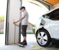 Zu sehen ist ein Mann beim Laden seines E-Autos. Die Ladeinfrastruktur in Mehrfamilienhäusern ist noch wenig entwickelt.