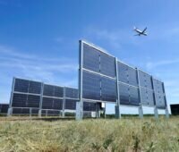 Senkrecht stehende Solarpanels unter einem abhebenden Flugzeug