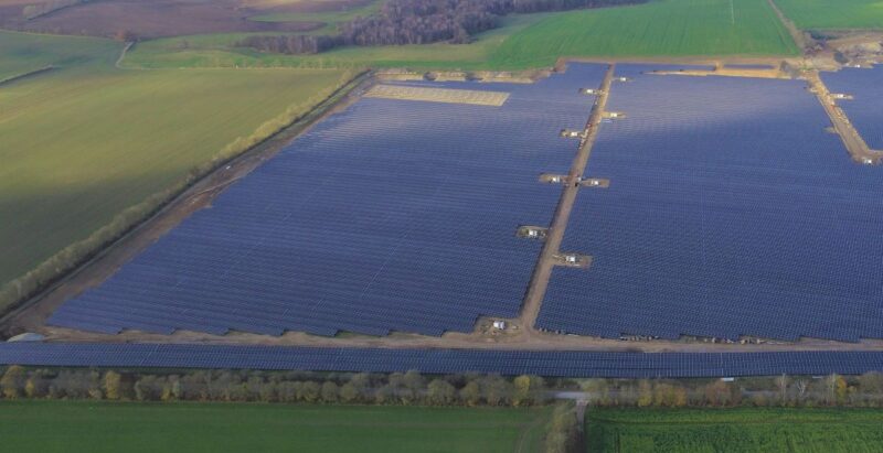 Luftbild einer großen PV-Freiflächenanlage auf grüner Wiese.