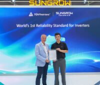 Zwei Vertreter von TÜV Rheinland und Sungrow präsentieren auf einem Messestand ein Zertifikat für neue Zuverlässigkeitsstandards von PV-Wechselrichtern. Im Hintergrund ist eine große Bildschirmwand mit den Logos beider Unternehmen zu sehen.