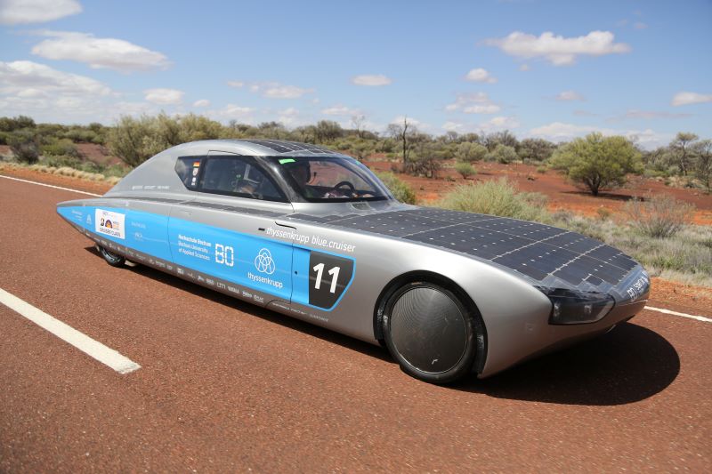 Ein Rennwagen mit Solarzellen auf einer Straße in der Wüste Australiens.