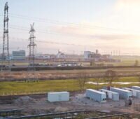 Batteriespeicher und PV-Anlage entlang einer Autobahn und Stromleitungen.