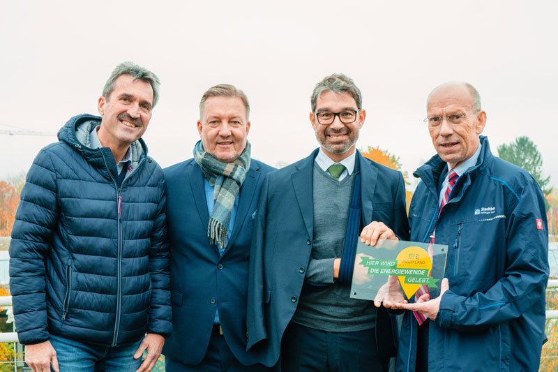 Vier Männer zeigen Ein Schild, Hier wird Energiewende gemacht: Sven Scherer, Prokurist Stadtwerke Ettlingen; Thomas Müller, Vorstand Baugemeinschaft Ettlingen eG; Staatssekretär Dr. Andre Baumann Steffen Neumeister, Geschäftsführer Stadtbau Ettlingen GmbH