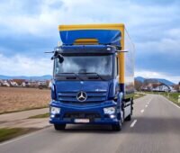 Ein Batterie-LKW in dörflicher Umgebung auf der Straße.