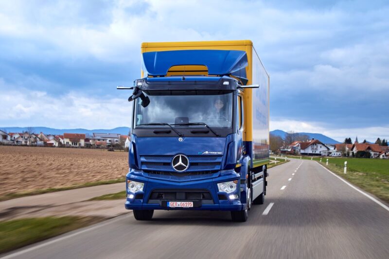 Ein Batterie-LKW in dörflicher Umgebung auf der Straße.