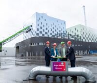 Vor dem neuen Biomasse-Heizkraftwerk Hannover stehen die Verantwortlichen und drücken einen symbolischen Knopf für den Start.