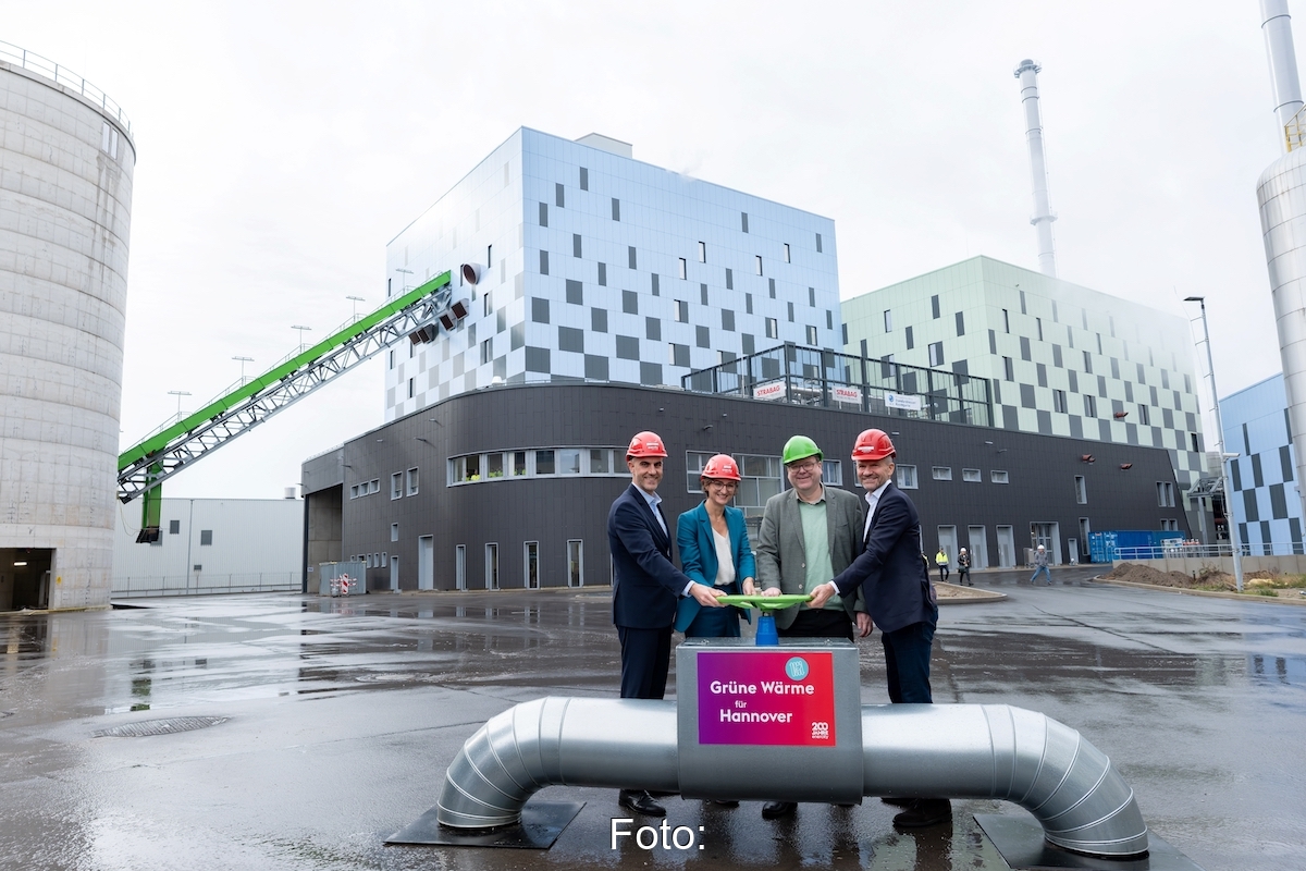 Vor dem neuen Biomasse-Heizkraftwerk Hannover stehen die Verantwortlichen und drücken einen symbolischen Knopf für den Start.