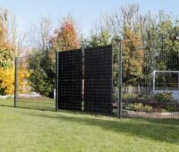 Zwei hochkant stehende PV-Module integriert in einen Zaun in blühendem Garten.