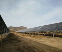 Eine Freiflächensolaranlage auf sandigem Boden.