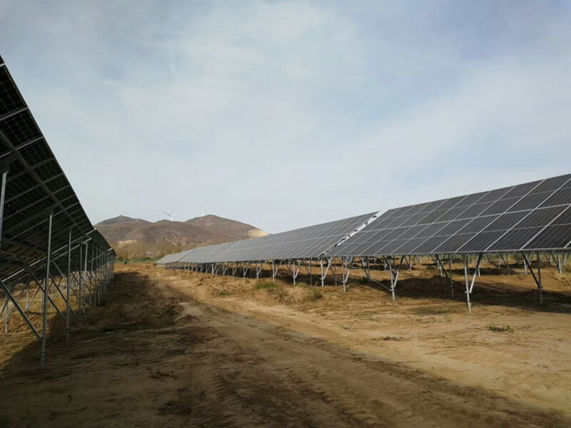 Eine Freiflächensolaranlage auf sandigem Boden.