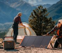 Das Bild zeigt zwei Camper in der Natur, die den Solargenerator 1500 Pro vor ihrem Zelt aufgebaut haben.