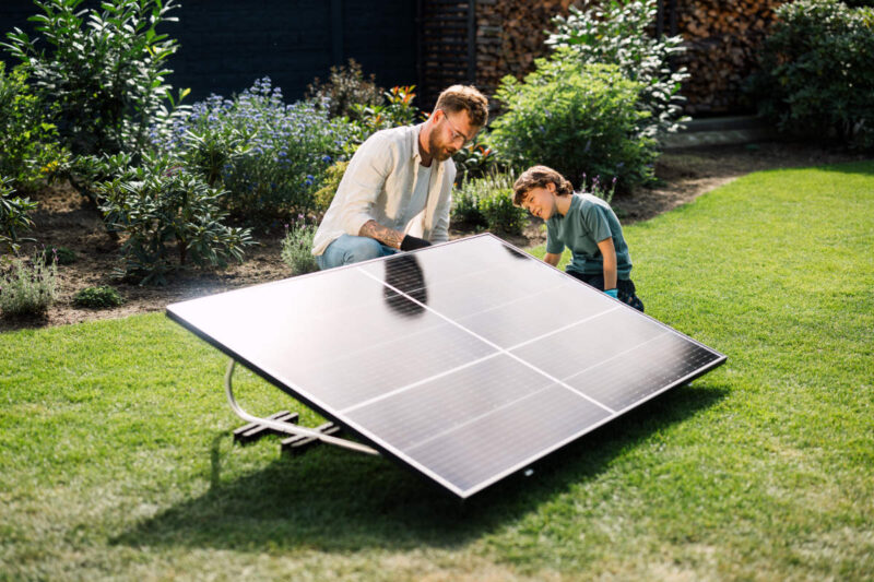 Ein Mann und ein Junge arbeiten auf dem Rasen an einem Balkonsolar-Modul
