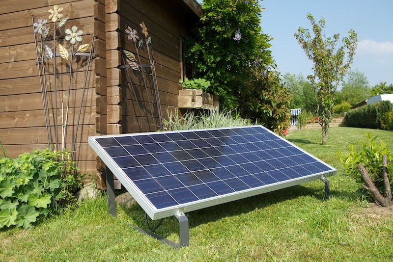 Ein Solarmodul vor einem Gartenhaus auf der Wiese