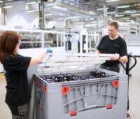 Eine Frau und ein Mann verstauen Solarzellen aus einem Werk in einer Box.