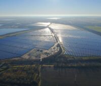 Luftbild eines 600 MW großen Solarparks bei tief stehender Sonne.