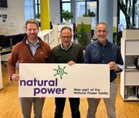 Drei Personen halten ein Schild in die Kamera: Natural Power ist jetzt das Zuhause von Renerco.