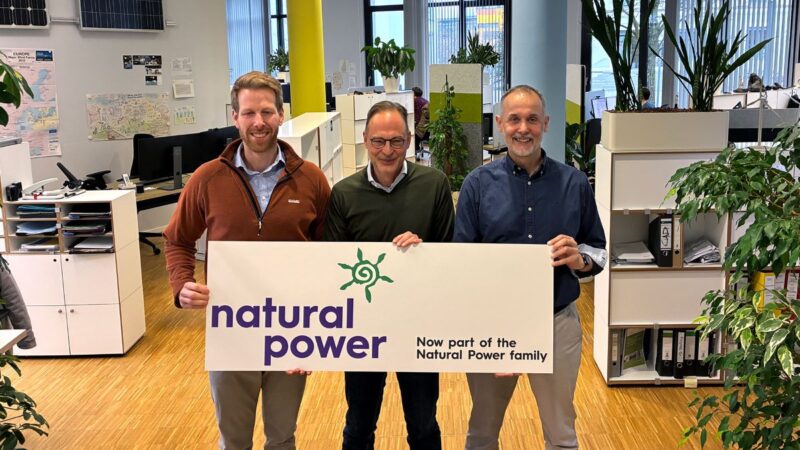 Drei Personen halten ein Schild in die Kamera: Natural Power ist jetzt das Zuhause von Renerco.