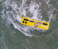 Ein Wellenkraftwerk-Prototyp in der Nordsee mit Gischt, aufgenommen aus der Luft