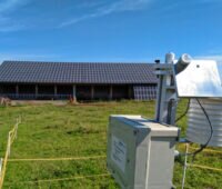 Messstation vor einer grünen Wiese unter blauem Himmel -