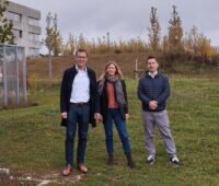 Das dreiköpfige Projektteam steht bei grauem Himmel auf der grünen Wiese im Energiepark der THU.