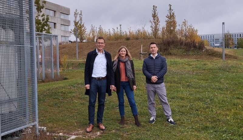 Das dreiköpfige Projektteam steht bei grauem Himmel auf der grünen Wiese im Energiepark der THU.