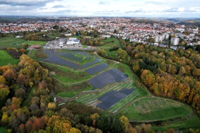Luftbild einer PV-Freiflächenanlage am Rande einer Kleinstadt.