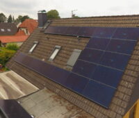 Eine PV-Anlage mit schwarzen Modulen auf einem Schrägdach eines Einfamilienhauses.