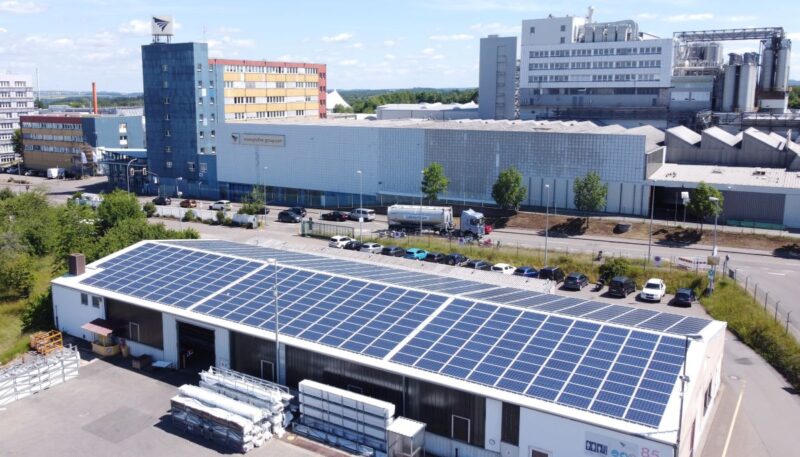 Ein Industriedach mit Photovoltaikanlage vor einem Chemiestandort.