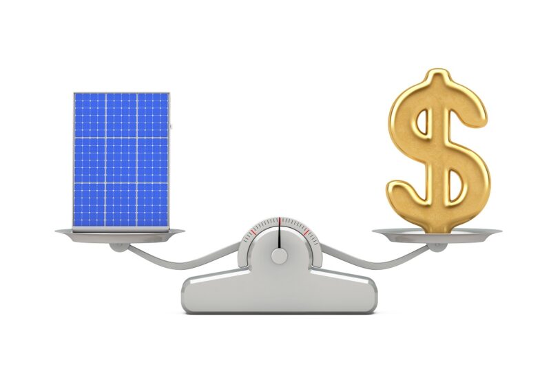 Zu sehen ist eine Waage, die PV-Module gegen Dollar aufwiegt als symbolische Darstellung der Preise für Photovoltaik-Module im November 2020.