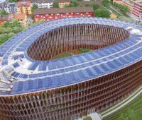 Neues, annähern ovales Rathaus Freiburg mit Photovoltaik auf dem Dach aus Vogelperspektive fotografiert