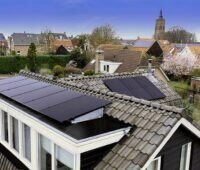 Haus mit Solarmodulen am Dach in einem Dorf mit Kirchturm.