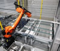 Roboter bewegt Solarmodul im Fertigungsumfeld.